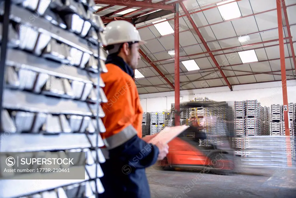 Warehouse workers moving stacked aluminum ingots