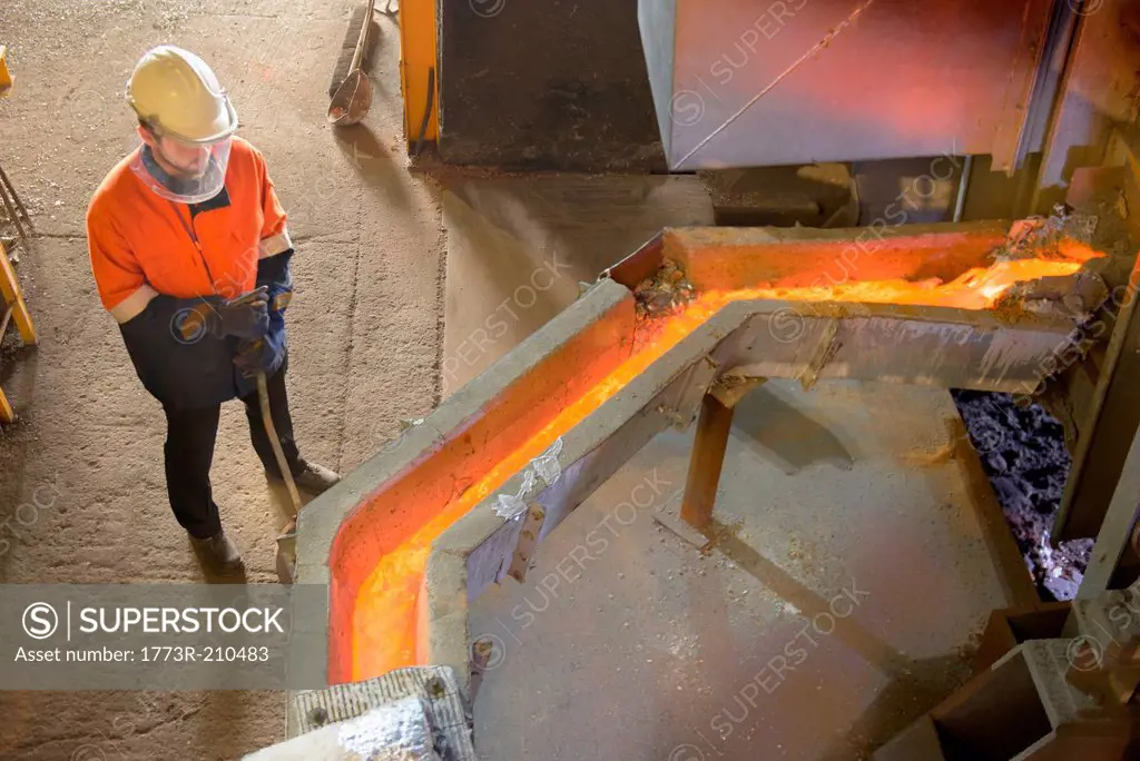 Worker monitoring molten metal at aluminum recycling plant