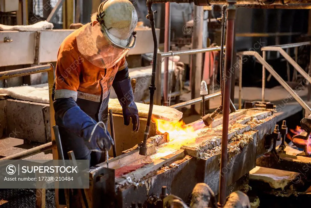 Worker testing molten metal at aluminum recycling plant