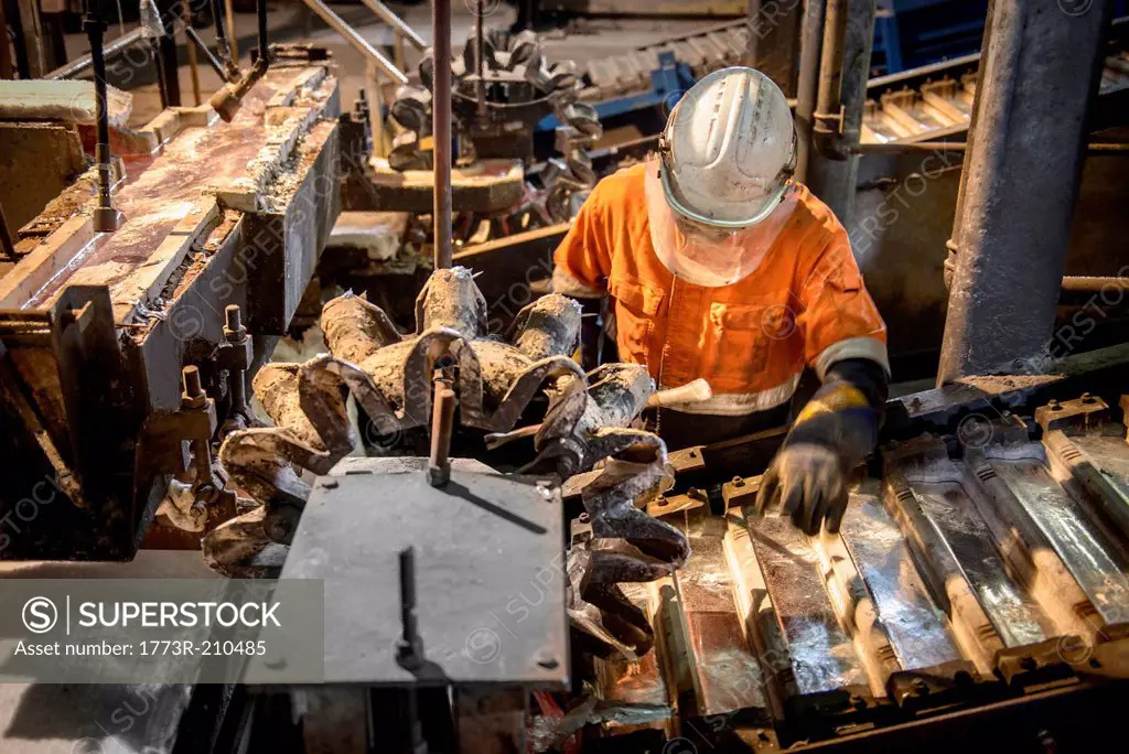 Worker testing metal ingots at aluminum recycling plant