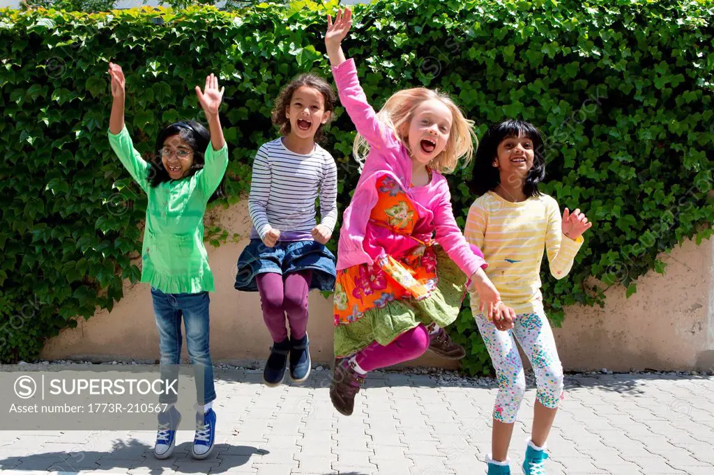 Four girls jumping in garden