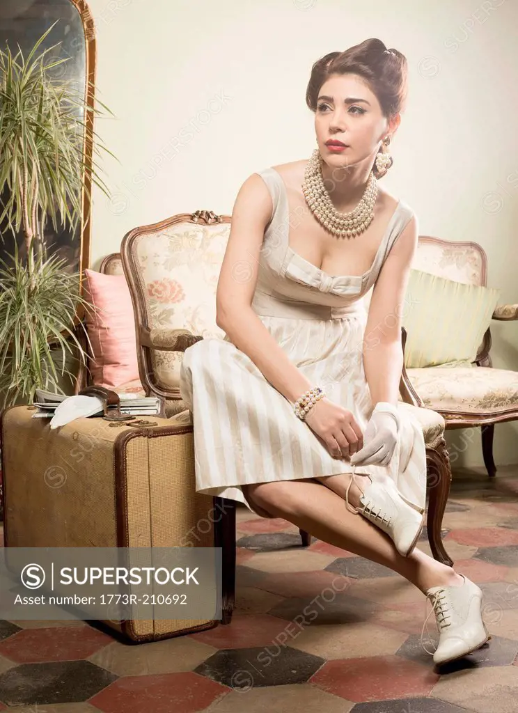Woman in vintage clothes waiting in lobby with suitcase