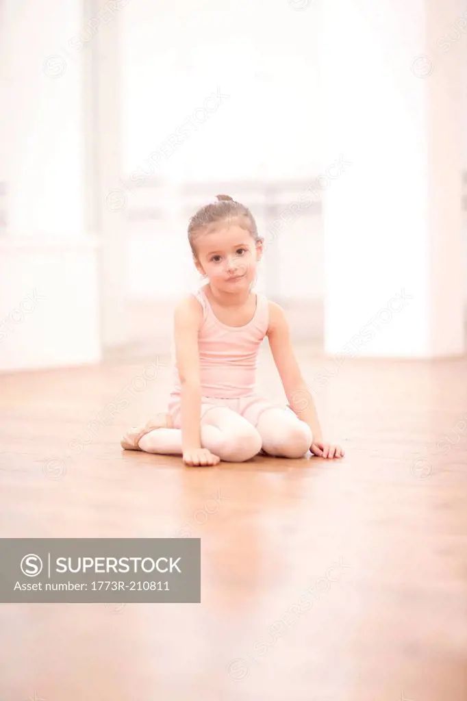 Portrait of young ballerina sitting on floor