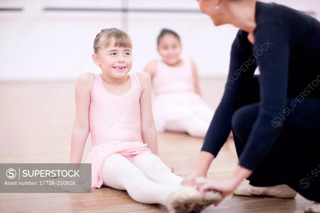 Teacher adjusting feet position of young ballerina