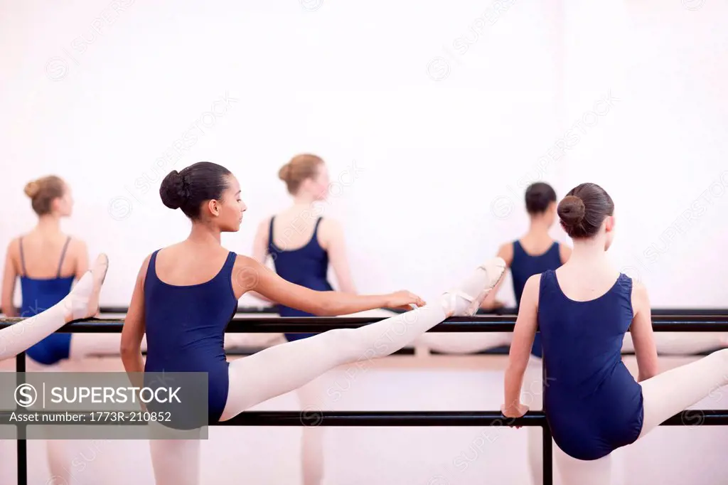 Group of teenage ballerinas practicing at the barre