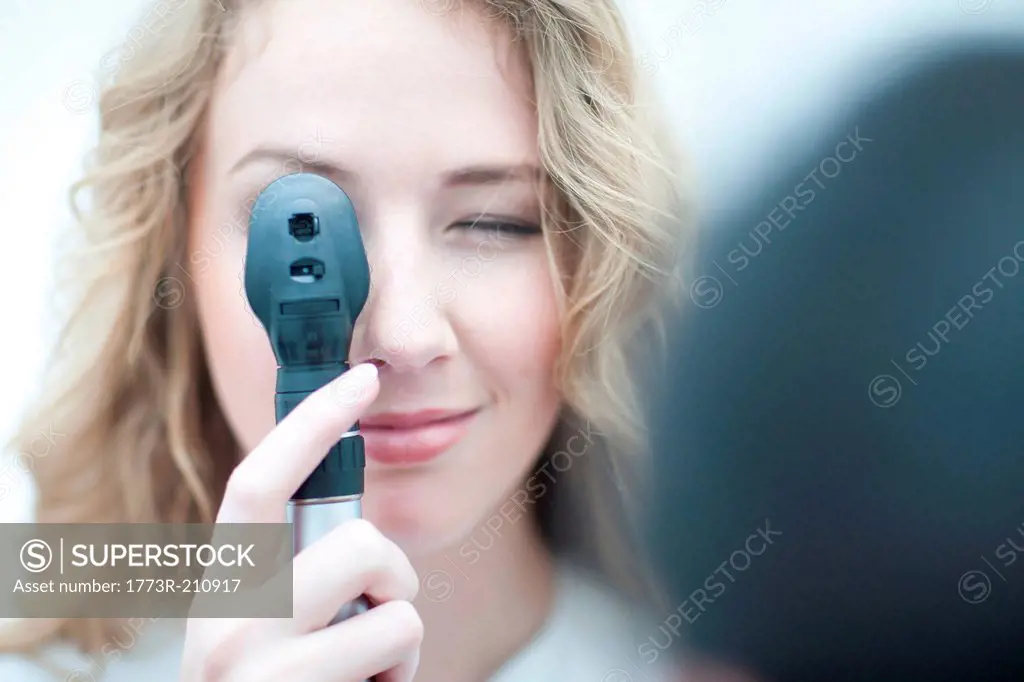 Close up of optician looking through ophthalmoscope