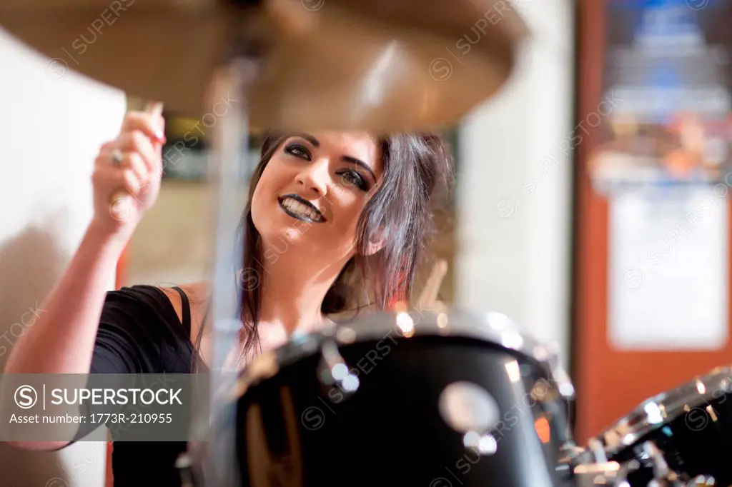 Young woman playing drum kit in music store