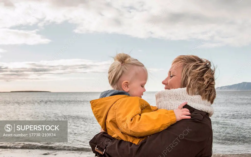 Grandmother and toddler hugging at coast