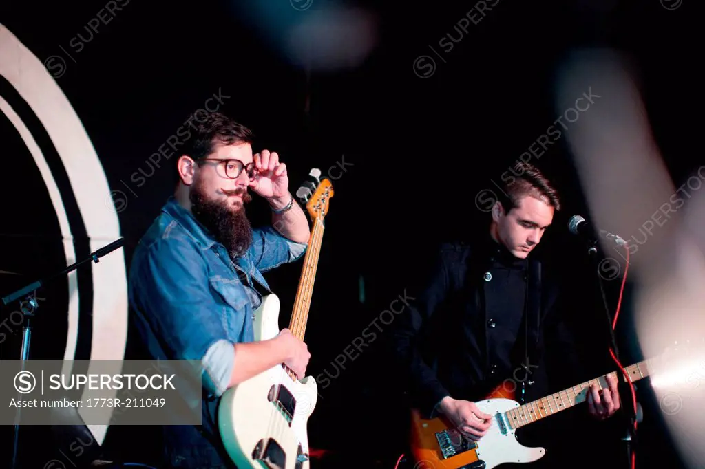 Two men playing guitars on stage