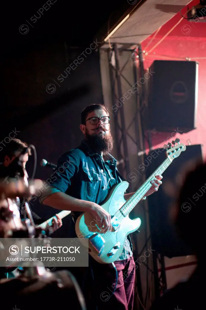 Men playing guitars on stage in club