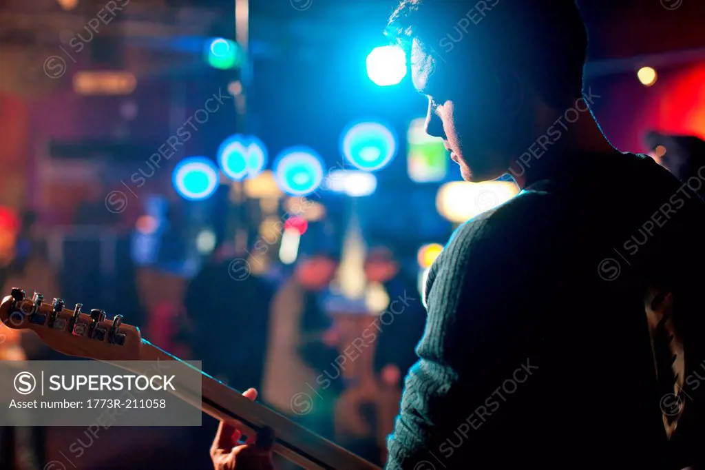 Man on stage playing guitar in nightclub