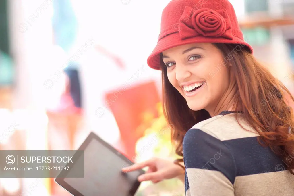 Woman in burgundy hat using digital tablet