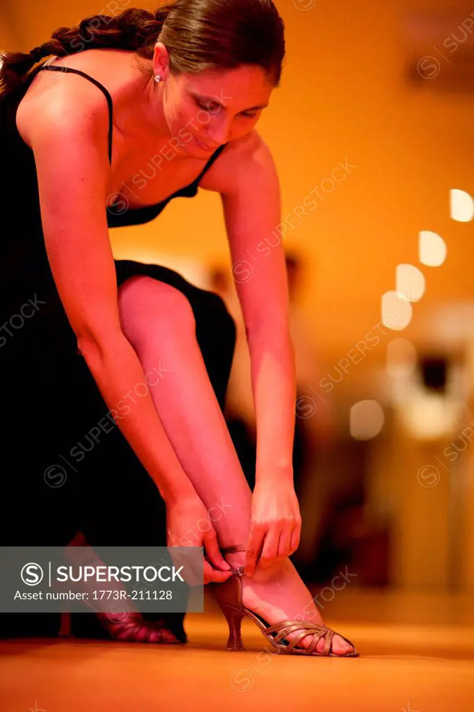 Mid adult woman adjusting strap of high heels
