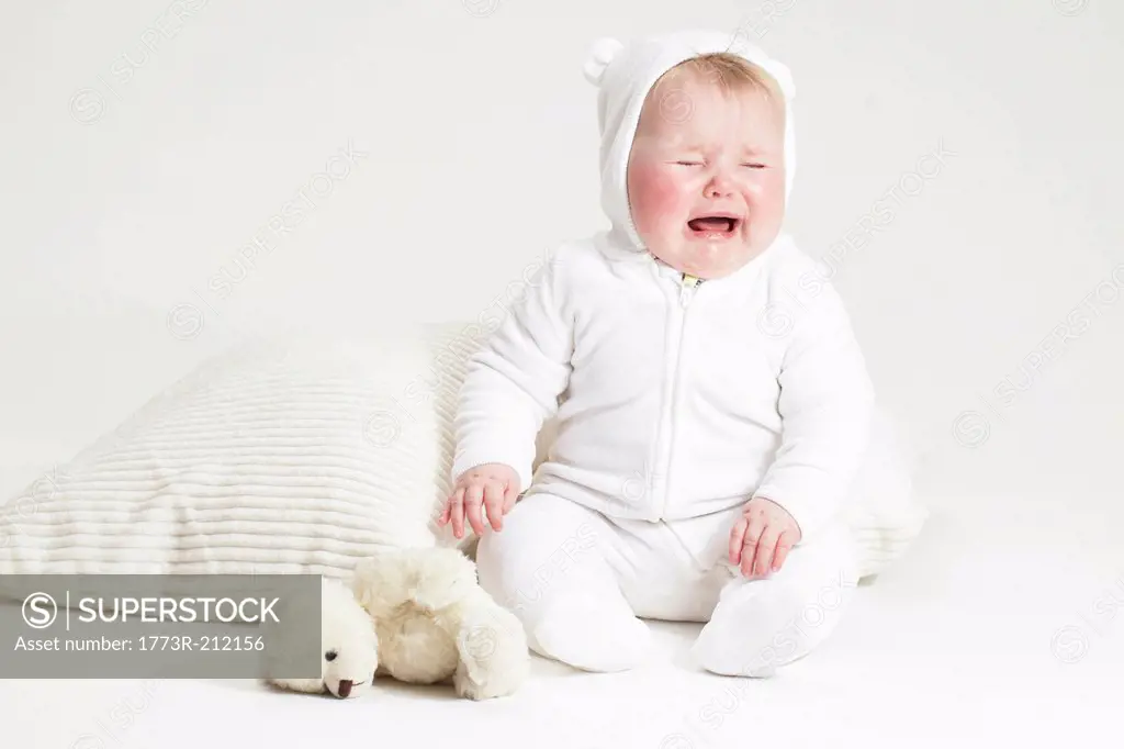 Portrait of crying baby girl and teddy bear