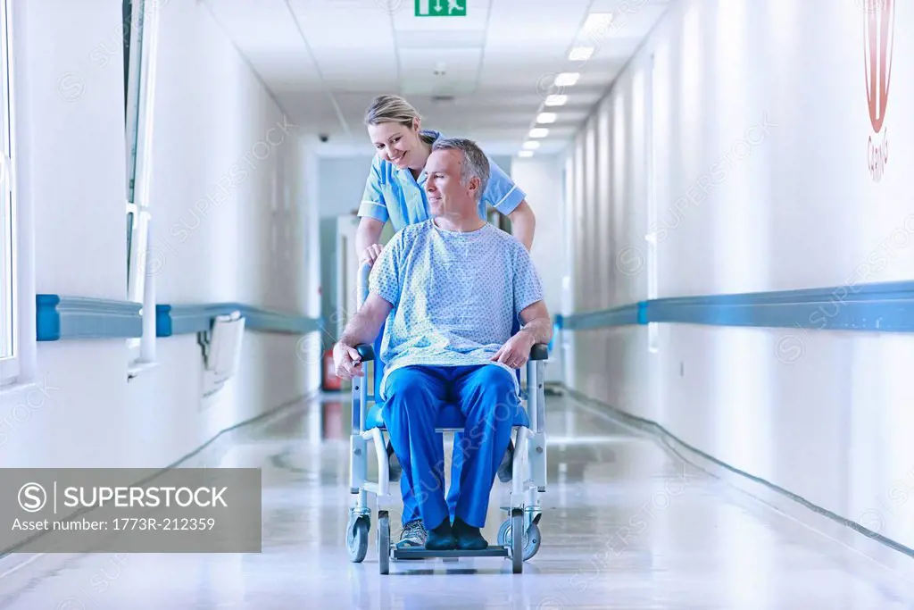 Nurse pushing patient in wheelchair down corridor