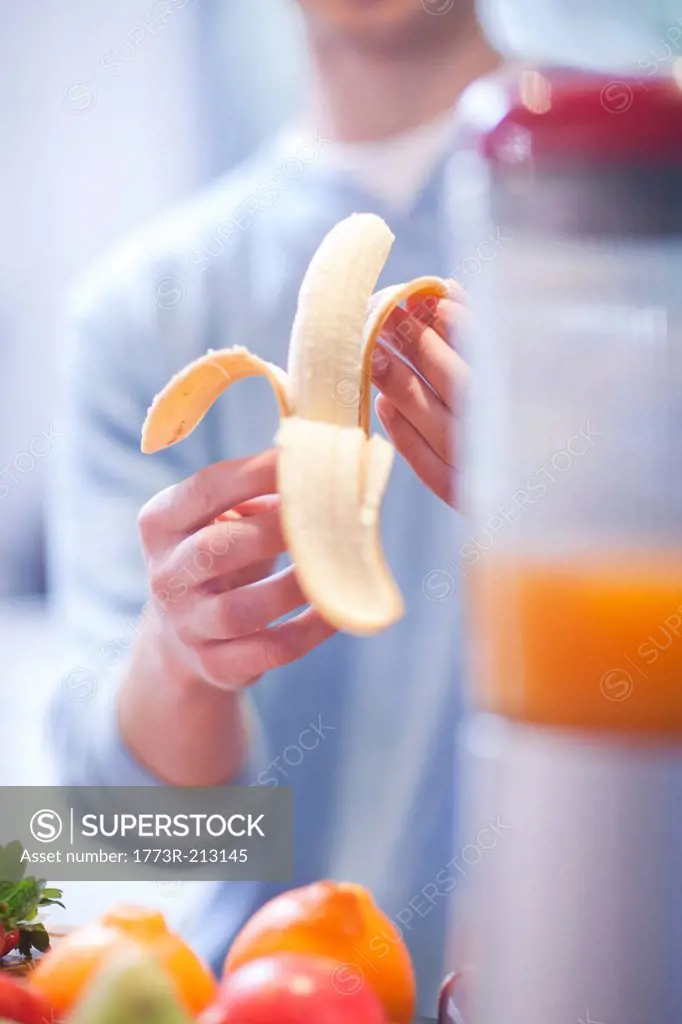 Young man peeling banana for fruit drink