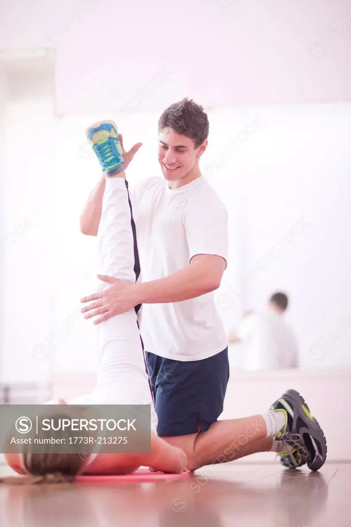 Young man training with client in gym