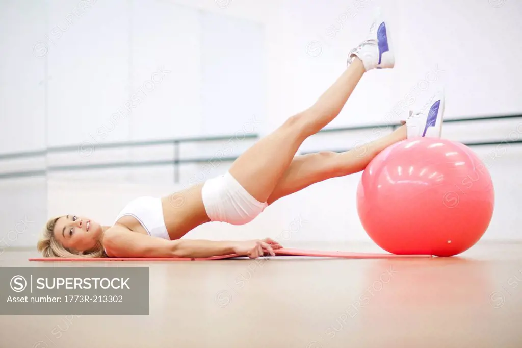 Young woman in gym training with exercise ball