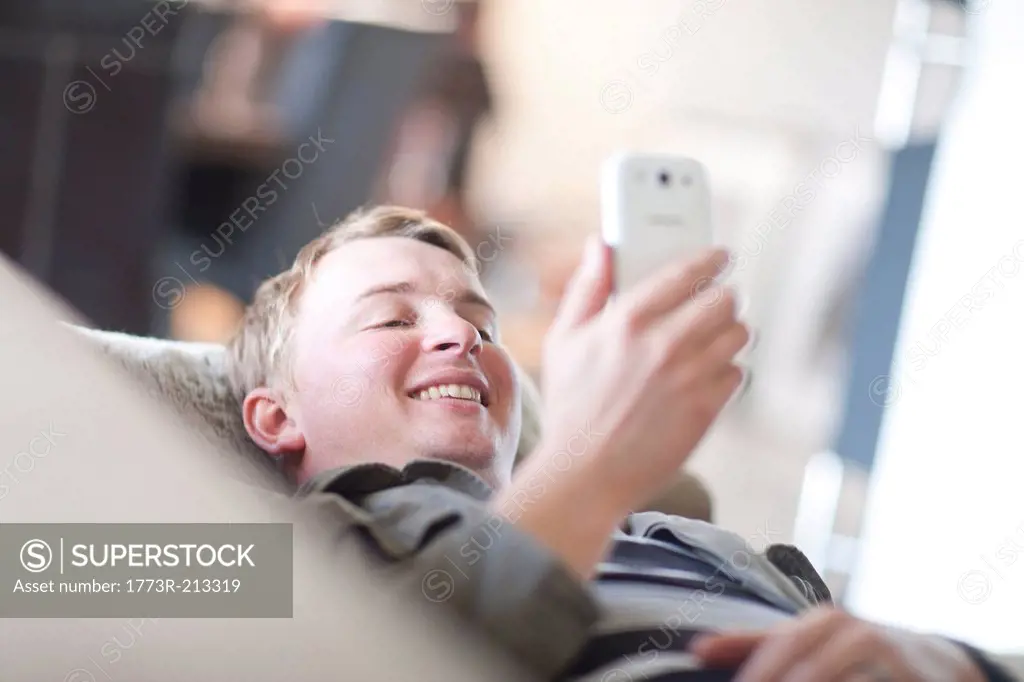 Man lounging on sofa looking at cellphone