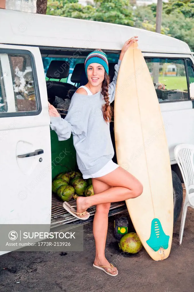 Young woman with surfboard by campervan