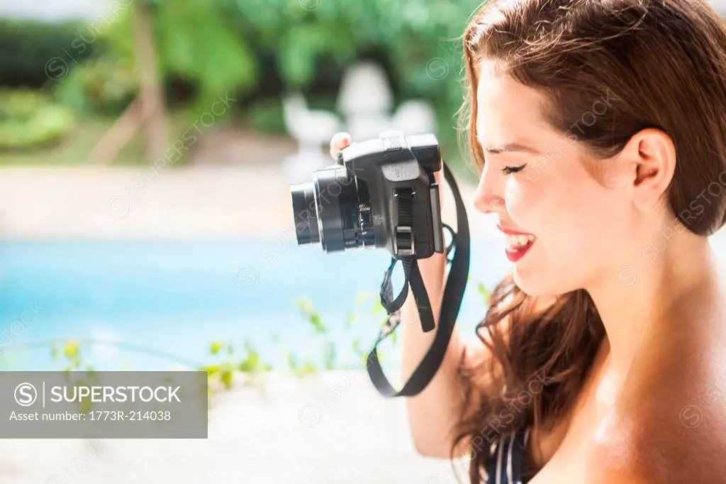 Young woman looking through camera viewfinder