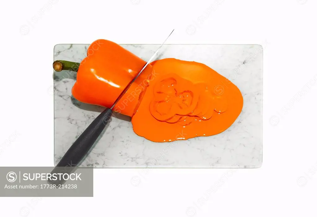 Kitchen knife cutting orange pepper