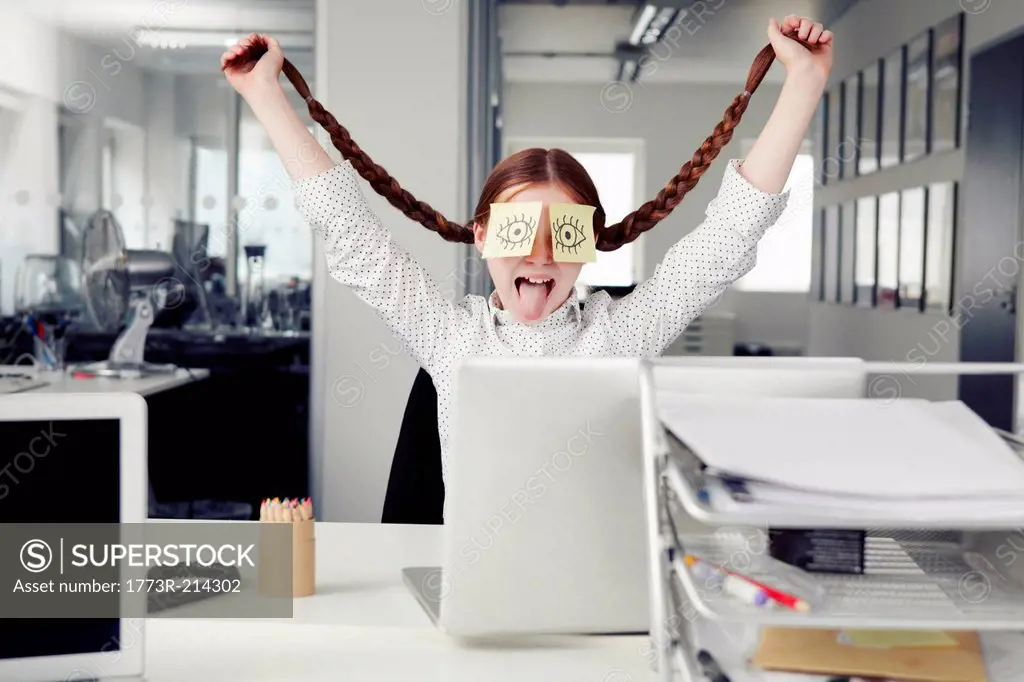 Girl in office with adhesive notes covering eyes holding plaits