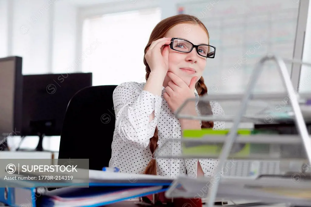 Girl wearing glasses with hand on chin in office