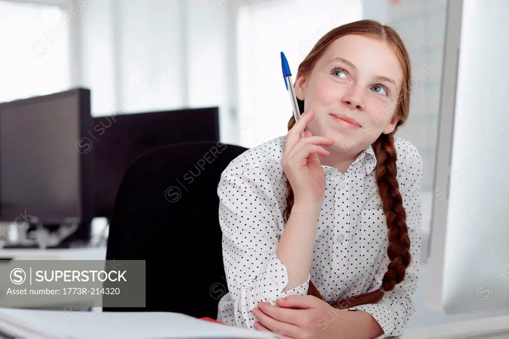 Girl holding biro and looking up in office