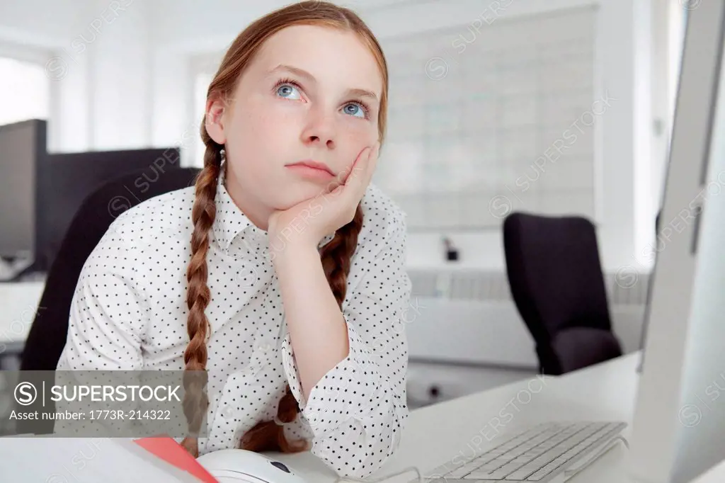 Girl with hand on chin looking up in office