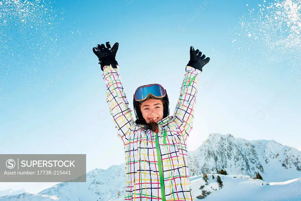 Portrait of teenage girl skier with arms raised, Les Arcs, Haute-Savoie, France