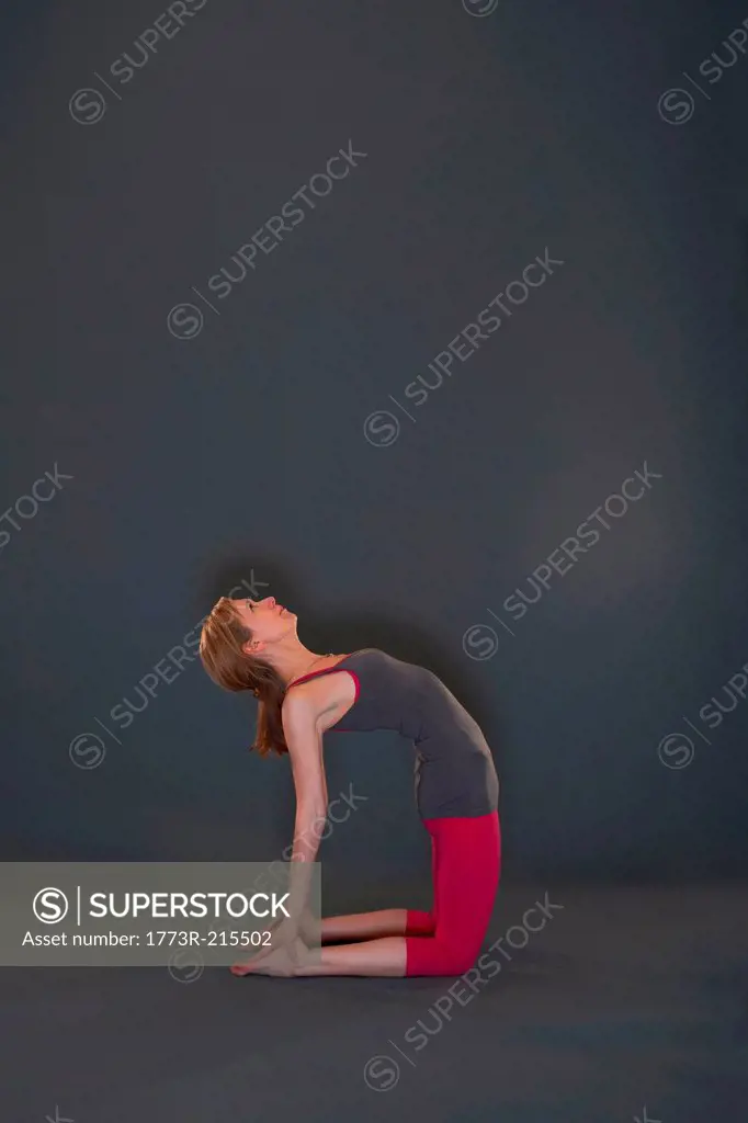 Woman in yoga pose on grey background