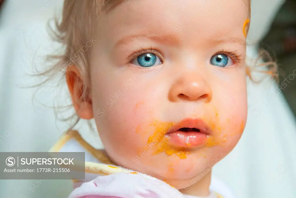 Baby girl with food on mouth