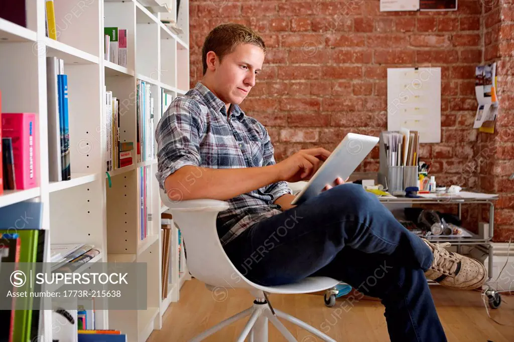 Young man sitting on chair using digital tablet