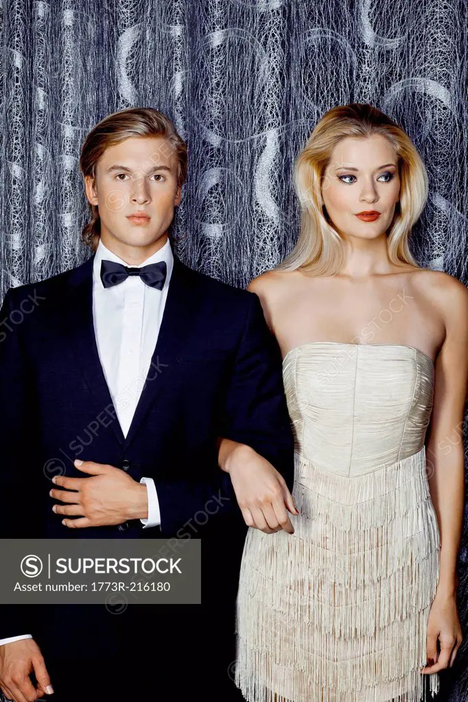 Serious young glamorous couple arm in arm