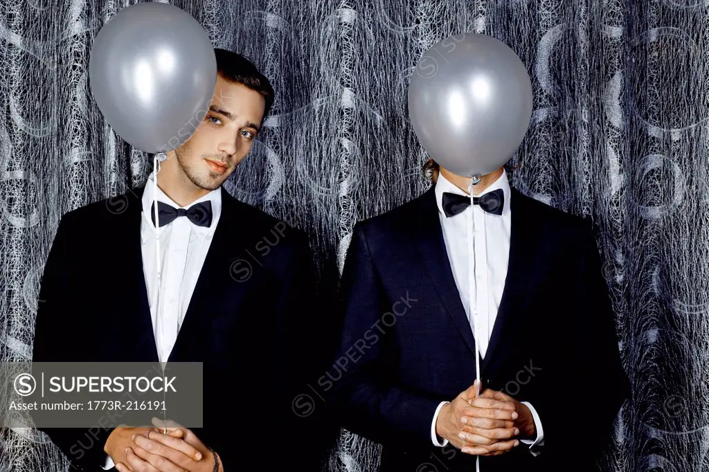 Two young men hiding behind balloons