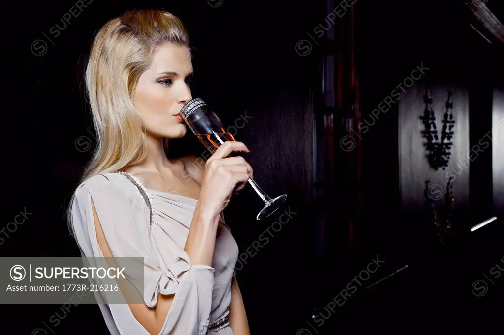 Young woman drinking alone in club