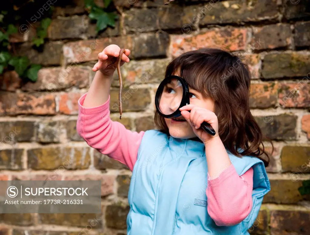 Girl looking at worm with magnifying glass