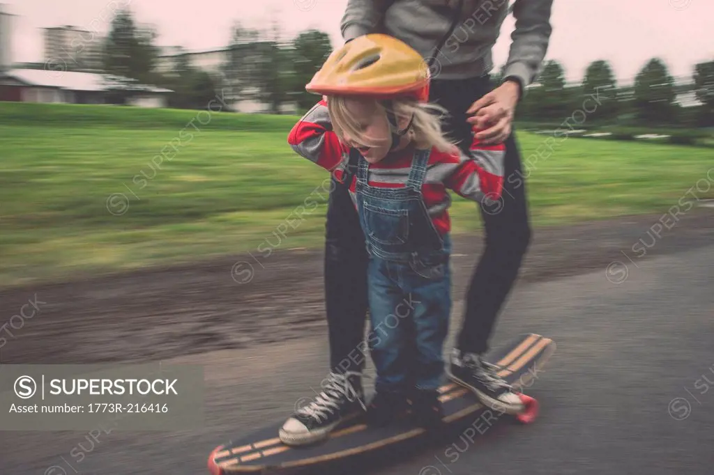Mother and daughter riding on skateboard in park