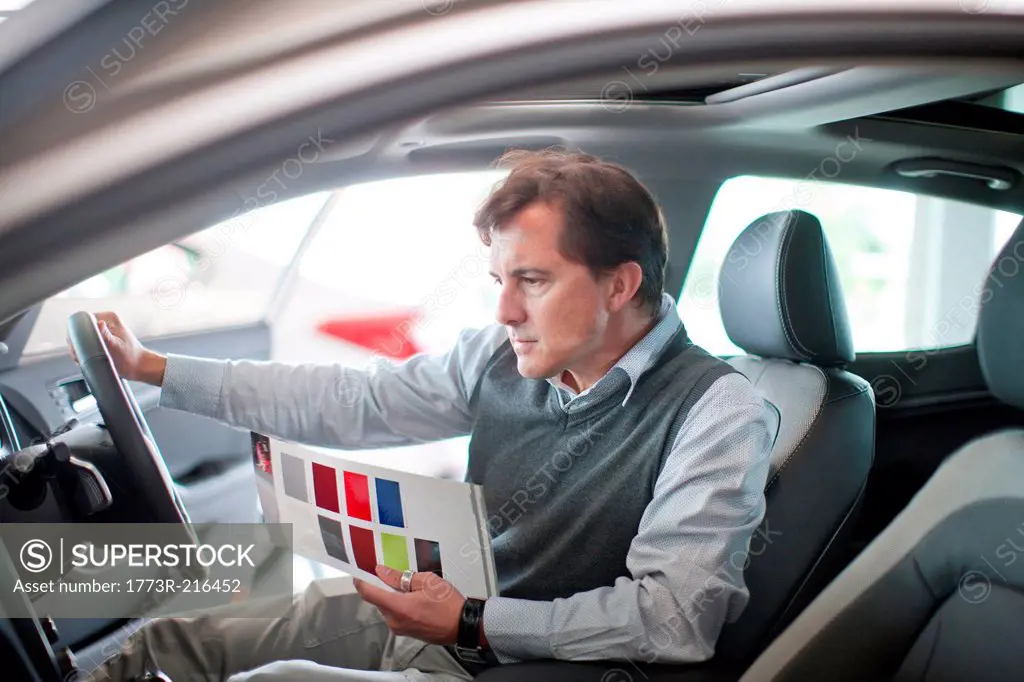 Mid adult man checking dashboard in car showroom