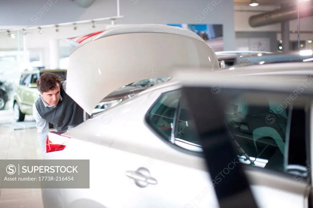 Mid adult man checking car boot in car showroom