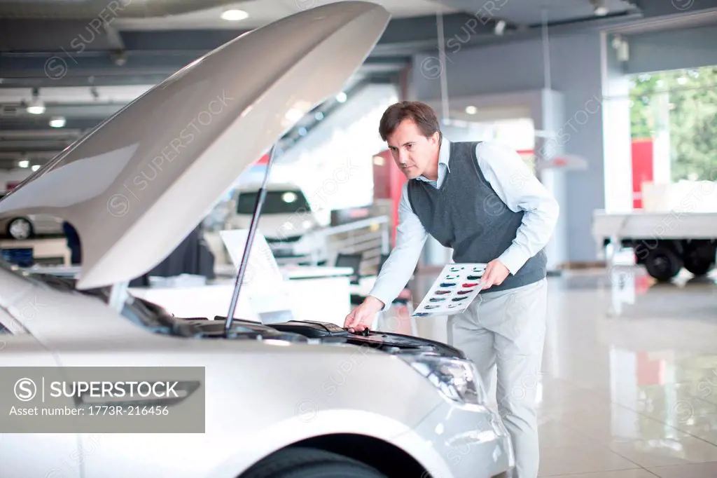 Mid adult man checking car bonnet in showroom