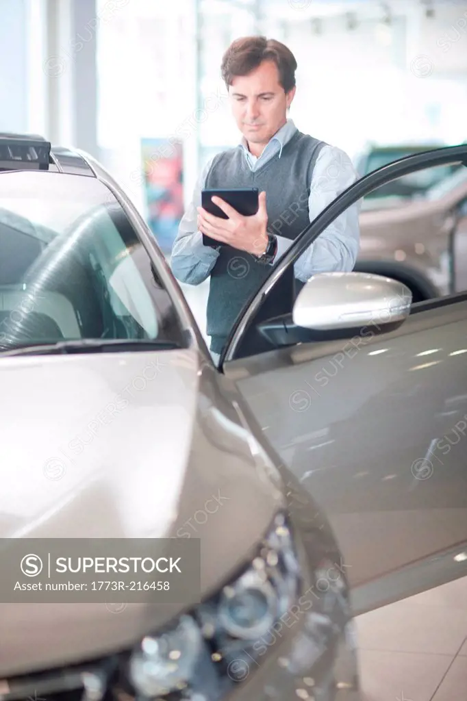 Mid adult man using calculator in car showroom