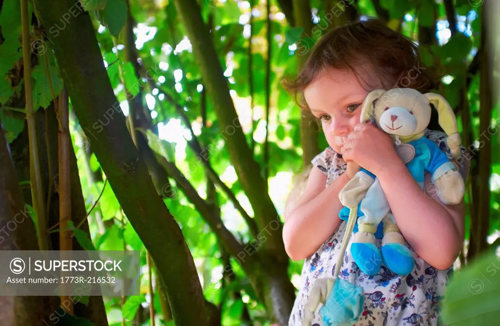 Portrait of female toddler with cuddly toy in woods
