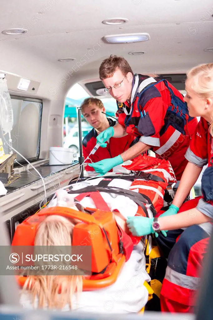 Paramedics with intravenous drip and patient in ambulance