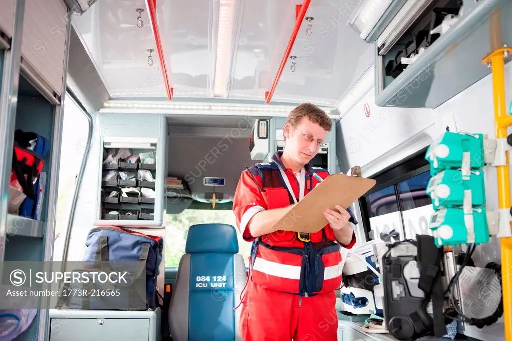 Paramedic in ambulance listing equipment