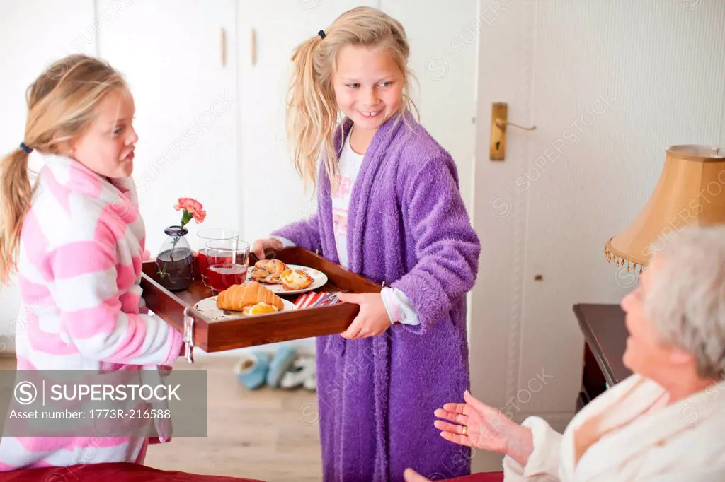 Granddaughters giving grandmother breakfast in bed