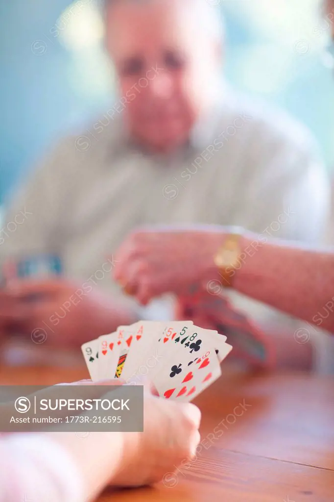 Senior male playing cards with family