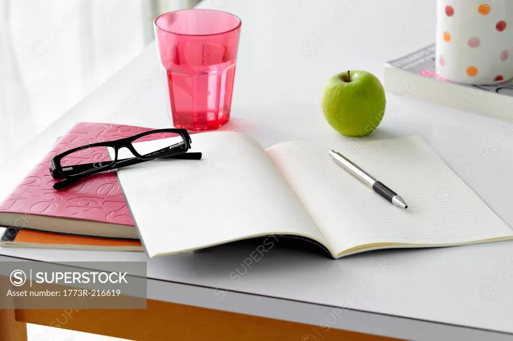 Kitchen table still life with notebooks, spectacles and apple