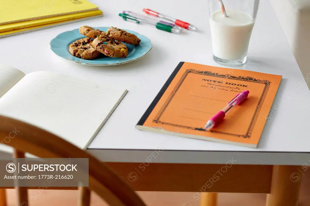 Kitchen table still life with notebooks, biscuits and milk